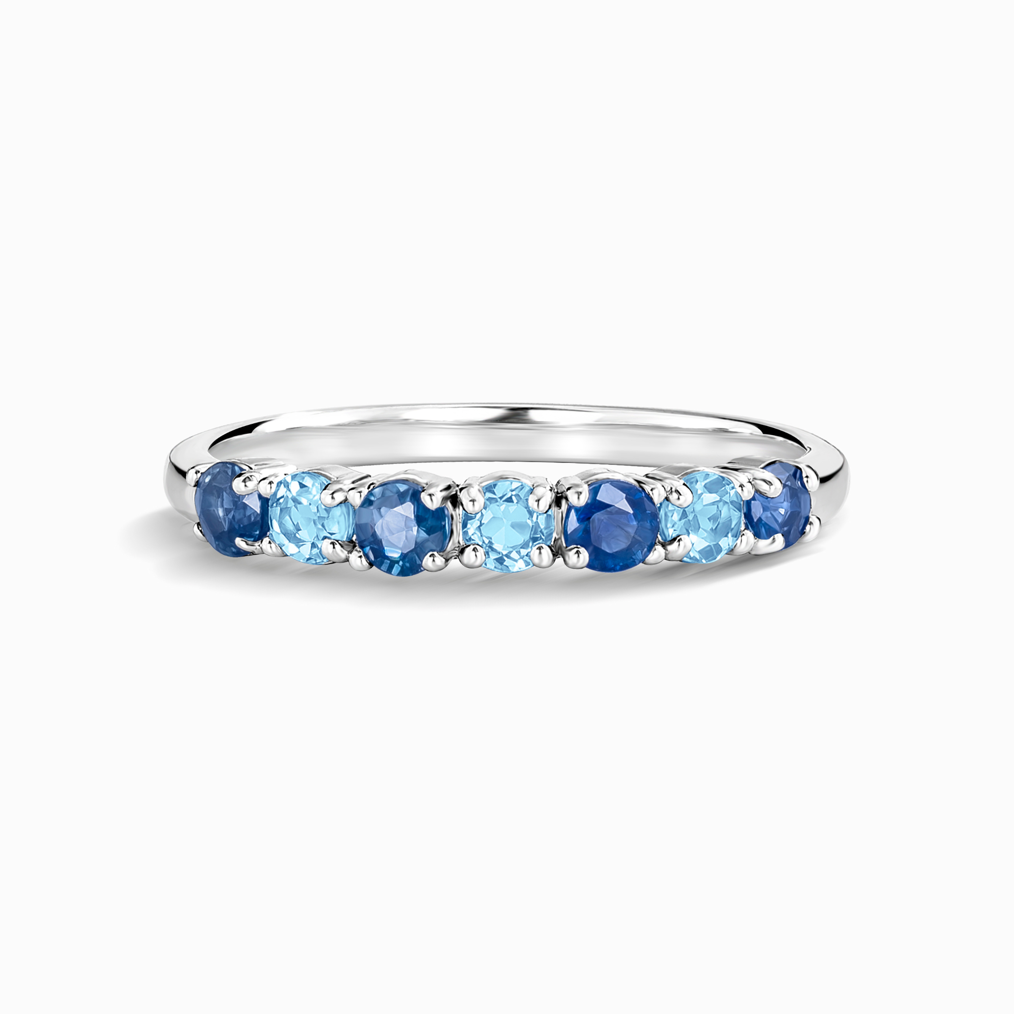Blue sapphire and blue topaz half eternity band in sterling silver on white background