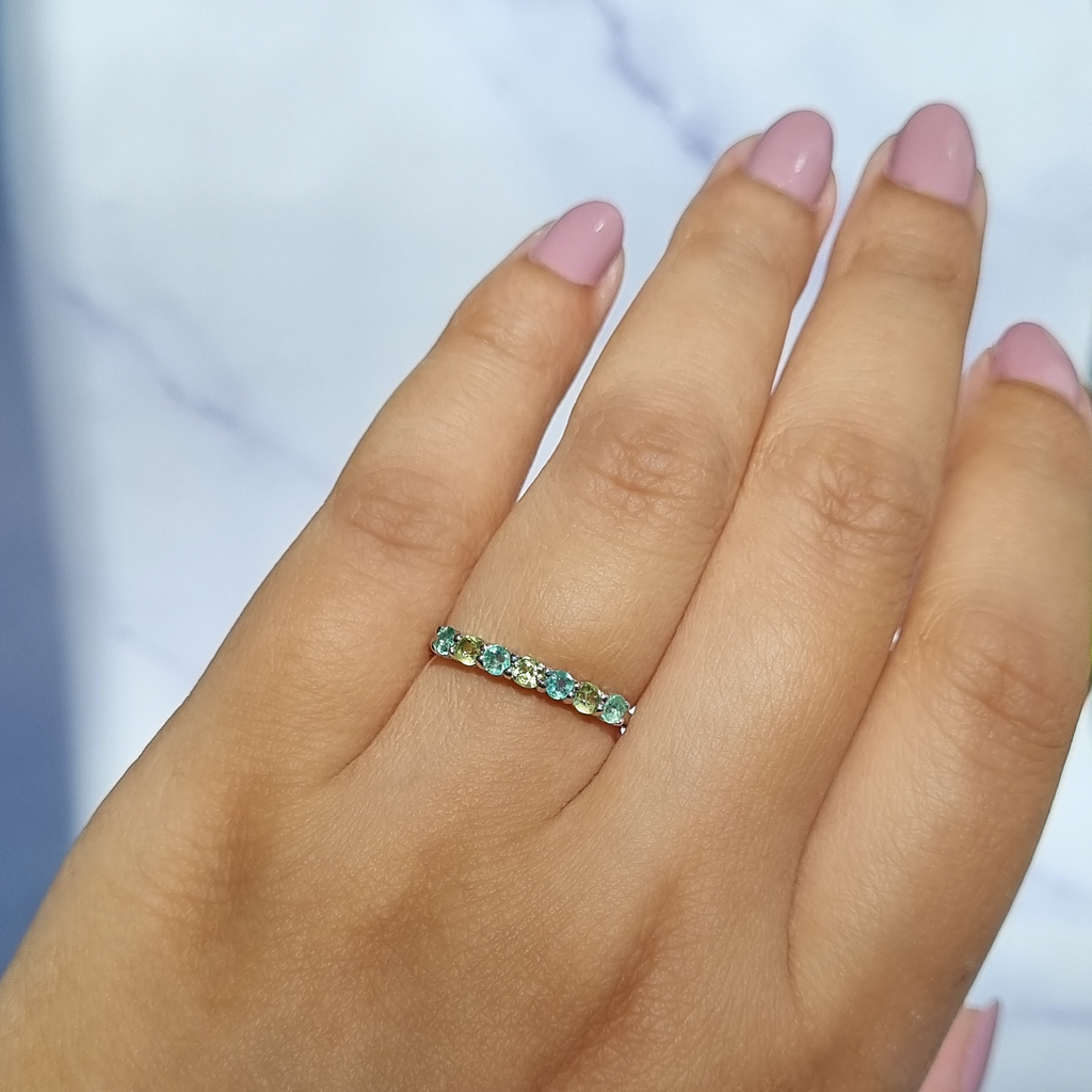 Emerald and peridot half eternity ring in sterling silver on hand detail image