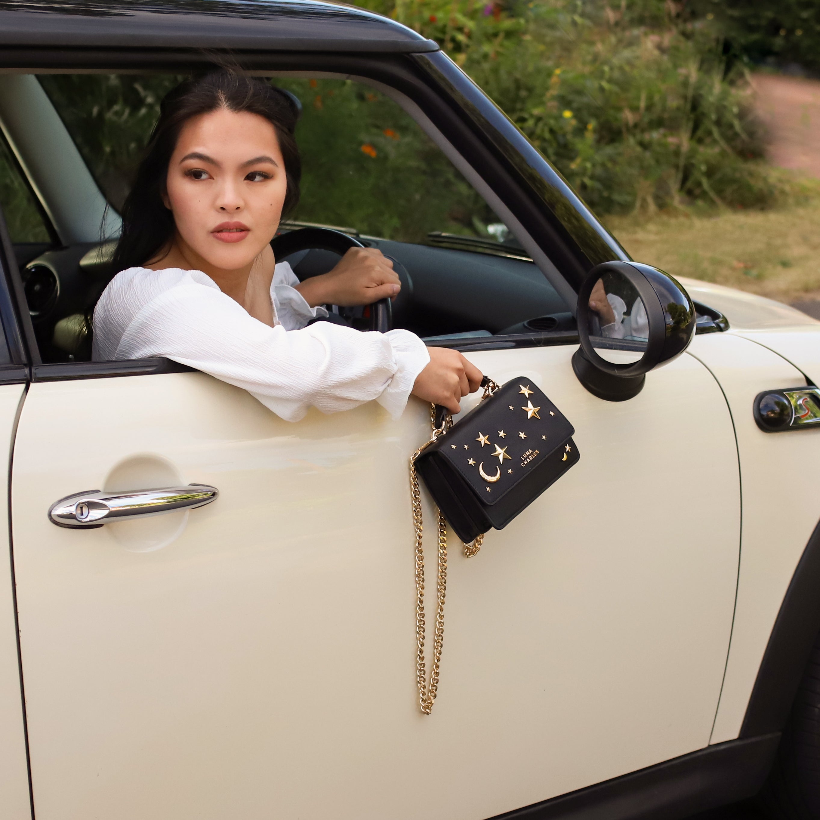 Luna Charles Nova black and gold crossbody bag in car lifestyle image