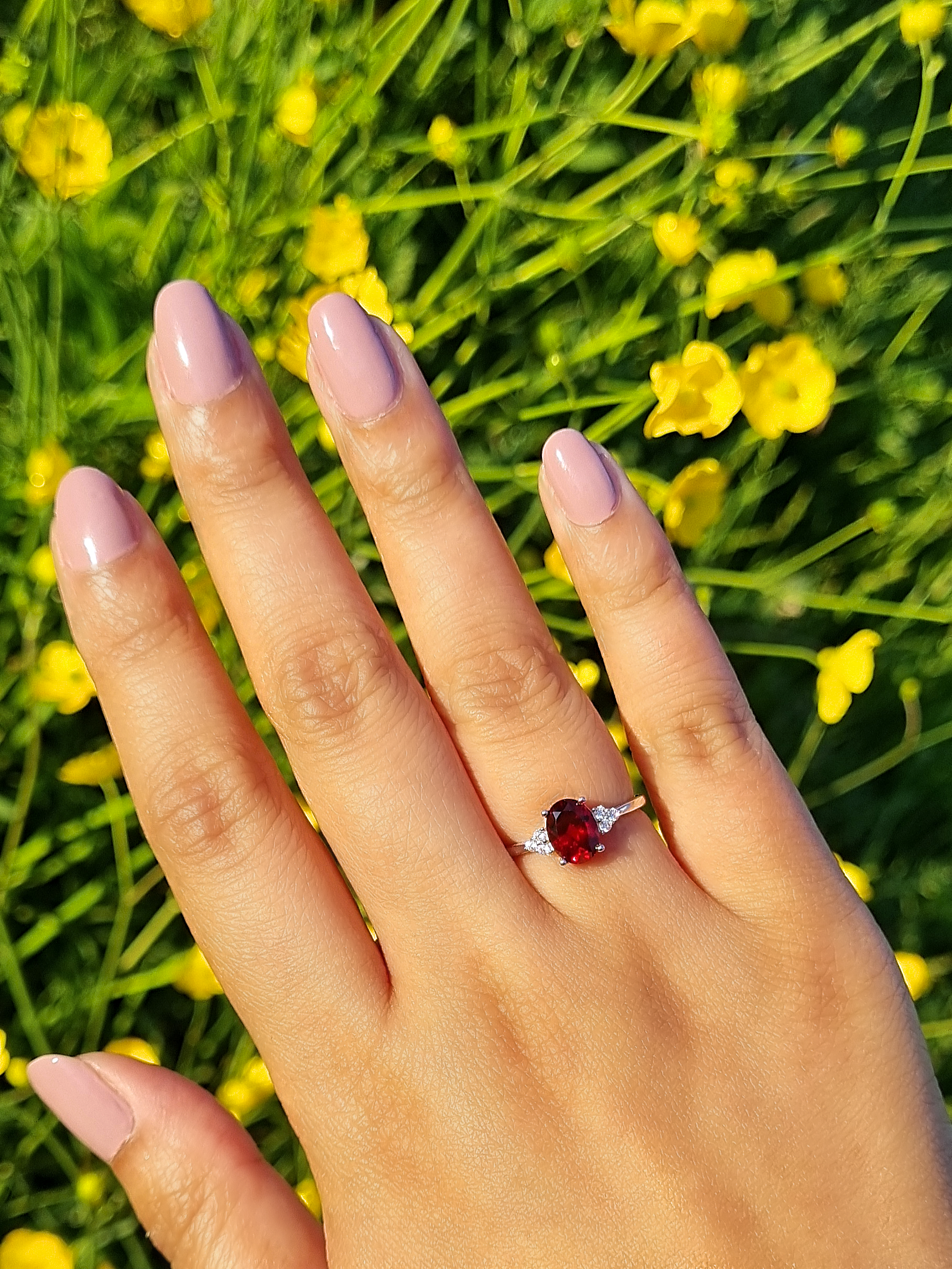 Garnet ring in sterling silver on hand with yellow flowers